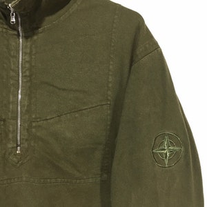 May include: A green, long-sleeved, zip-up sweatshirt with a compass logo on the left sleeve.