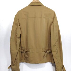 May include: A brown cotton jacket with a zipper closure and a belt at the waist. The jacket has long sleeves with buttoned cuffs.