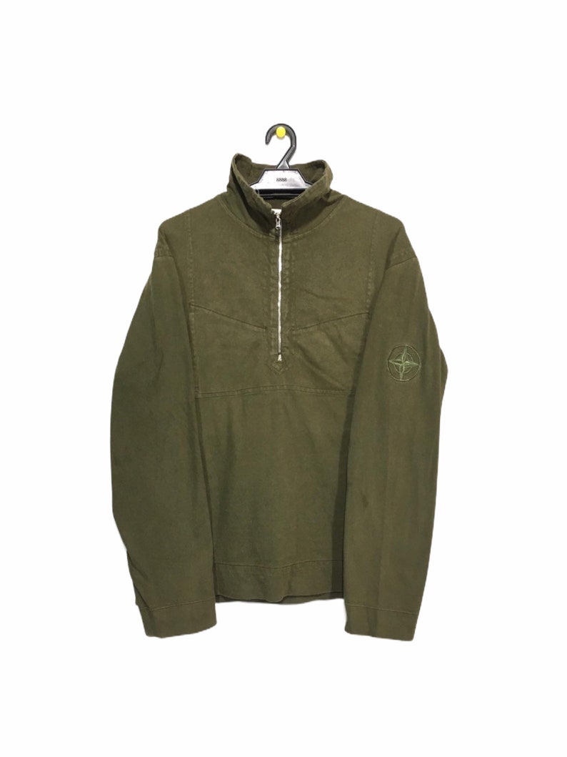 May include: A green long-sleeve zip-up sweatshirt with a compass logo on the left sleeve.