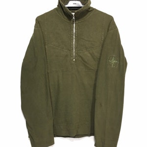 May include: A green long-sleeve shirt with a half-zip closure and a compass logo on the left sleeve.