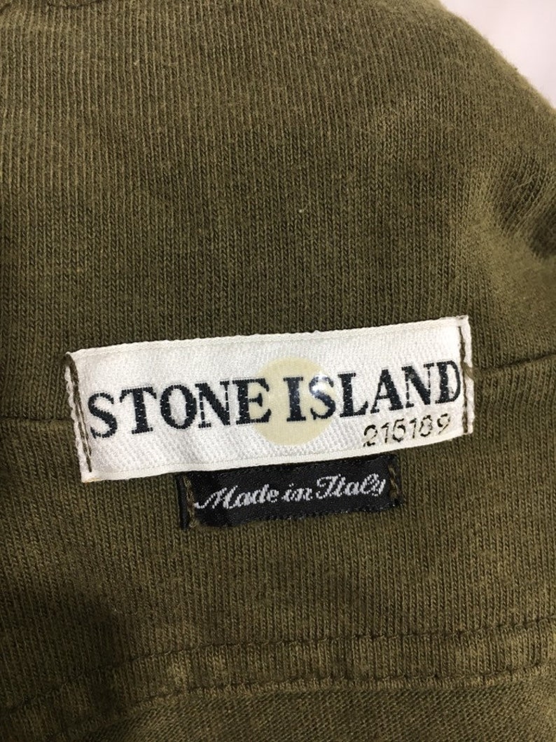 May include: A white label with the text "STONE ISLAND" and a compass logo. The label also has the text "215189" and "Made in Italy" in black.