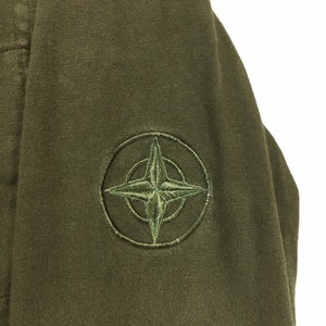 May include: A green hooded sweatshirt with a compass logo embroidered on the left sleeve.