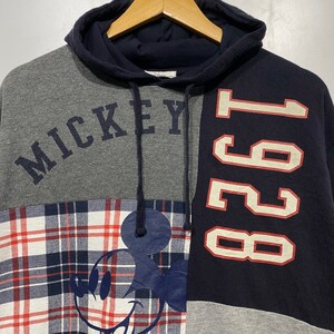 Puede incluir: Una sudadera con capucha de color gris, azul y rojo con un dise&ntilde;o de Mickey Mouse y el texto "Mickey" y "1991".
