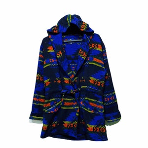 Puede incluir: Una bata azul con capucha y un estampado geométrico colorido. La bata tiene un cinturón de atar y mangas largas.