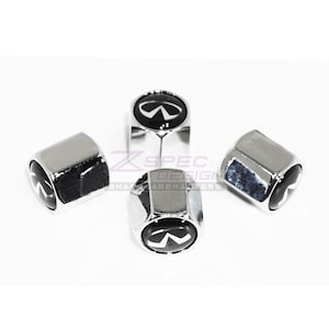 May include: Four chrome-finished tire valve stem caps with the Infiniti logo in black and white. The caps are hexagonal and have a shiny, reflective surface. The caps are arranged on a white background.