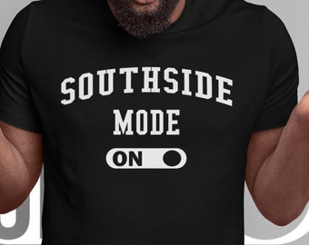 May include: A man wearing a black t-shirt with the text "Southside Mode On" in white lettering. The man is looking at the camera with a surprised expression. He is wearing a black beanie and has a beard.