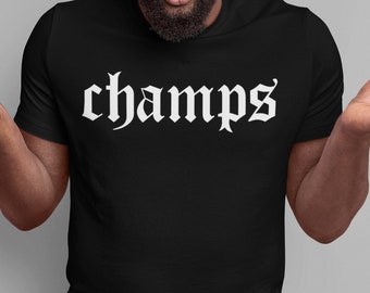 May include: A black t-shirt with the word "champs" printed in white in a gothic font. The person wearing the shirt is looking surprised and has their hands up in the air.