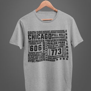 K&ouml;nnte beinhalten: Ein hellgraues T-Shirt mit einem schwarzen Aufdruck, der das Wort "CHICAGO" und verschiedene Stadtteilnamen sowie Postleitzahlen zeigt. Das T-Shirt h&auml;ngt an einem Holzkleiderb&uuml;gel.