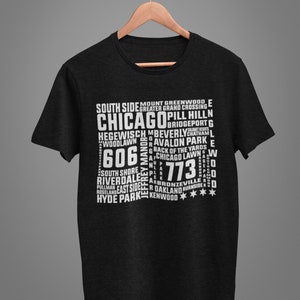 K&ouml;nnte beinhalten: Schwarzes T-Shirt mit einem wei&szlig;en Aufdruck mit dem Stadtnamen "Chicago" und verschiedenen Stadtteilnamen sowie den Postleitzahlen 606 und 773. Das Shirt h&auml;ngt an einem Holzb&uuml;gel.