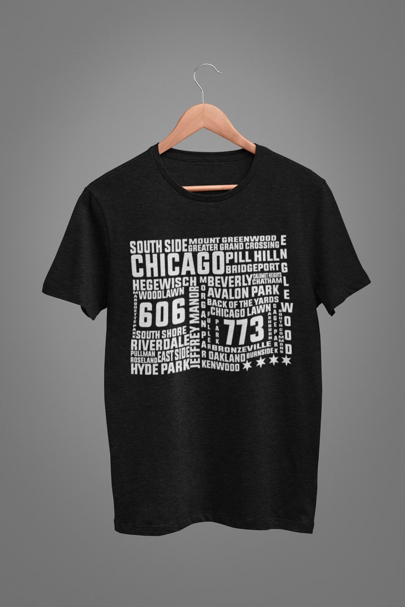 K&ouml;nnte beinhalten: Schwarzes T-Shirt mit einem wei&szlig;en Aufdruck mit dem Stadtnamen "Chicago" und verschiedenen Stadtteilnamen sowie den Postleitzahlen 606 und 773. Das Shirt h&auml;ngt an einem Holzb&uuml;gel.