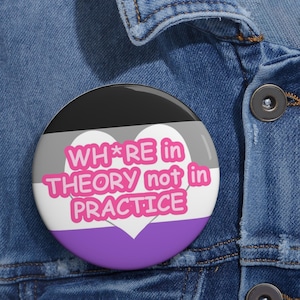 Peut inclure: Un bouton rond avec un design de cœur noir, gris, blanc et violet. Le texte sur le bouton est "WH*RE in THEORY not in PRACTICE".