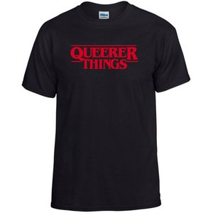 以下が含まれることがあります： 「Queerer Things」という赤い文字が書かれた黒いTシャツ。人気番組「Stranger Things」のパロディーです。