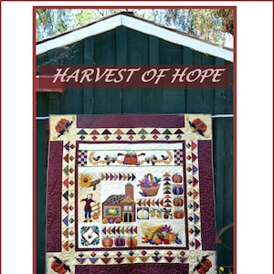 May include: A quilt titled "Harvest of Hope" by Sew'n Wild Oaks, featuring a farmhouse, pumpkins, and other autumnal imagery. The quilt is displayed against a green wooden shed.