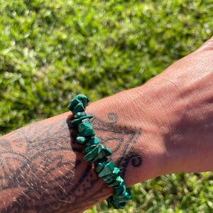 May include: A green malachite chip bracelet. The bracelet is made of small, irregular pieces of malachite that are strung together on a clear elastic cord.