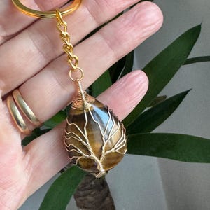 Tigerauge Kristall Schlüsselanhänger. Natürlicher Tigerauge Kristall. Draht gewickelt mit goldenem Lebensbaum Kristall. Fertig zum Verschenken in einer Geschenkschachtel mit Schleife.