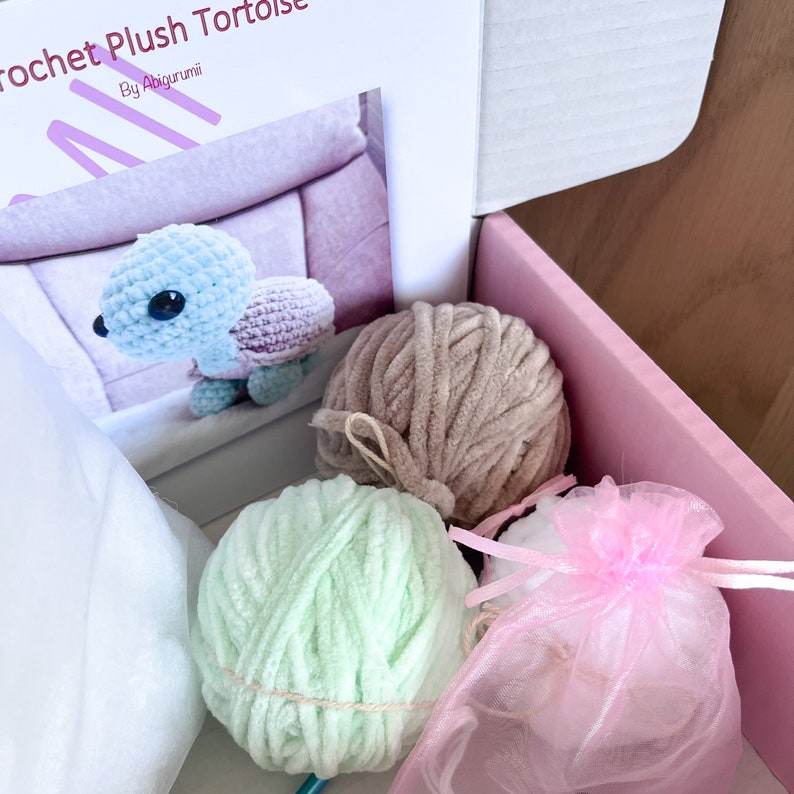 Puede incluir: Un kit de tortuga de peluche de crochet con hilo azul claro, rosa y marr&oacute;n, relleno blanco y una bolsa de tul rosa. El kit incluye instrucciones para tejer una tortuga de peluche.