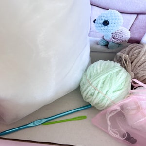 Puede incluir: Un kit de crochet con una bola de hilo verde claro, una bolsa de malla rosa, una tortuga de crochet azul claro, un gancho de crochet verde y un gancho de crochet de 5,0 mm.