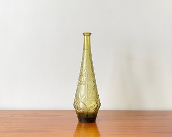 Peut inclure: Une bouteille en verre vert olive, haute et élancée, présentant une surface texturée avec des motifs de fruits en relief, notamment des cerises et des feuilles. La bouteille possède un col étroit et une base légèrement évasée.