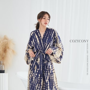 Puede incluir: Una larga bata de kimono de color azul marino y crema con estampado tie-dye y cinturón de anudar. La bata está hecha de rayón suave y tiene un corte holgado. El nombre de la marca "COZYCONY" está impreso en el lado derecho de la imagen. El texto "TIE DYED LONG KIMONO - SOFT RAYON" está impreso en el lado derecho de la imagen.