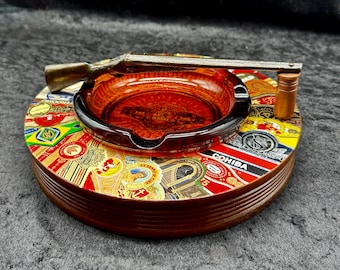 Cenicero antiguo de los años 40 de 23,5 cm con escopeta decorativa y anilla de cigarro original.