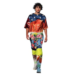 May include: A person wearing a red, white and blue patterned shirt with floral print trousers. The shirt has a star pattern and the trousers have a colourful floral design.