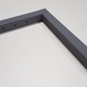 May include: A grey metal corner brace with five holes drilled into the top side.
