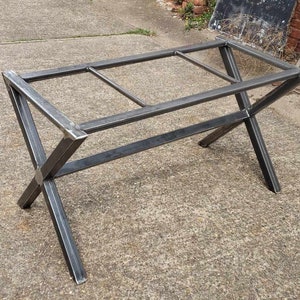 May include: A metal table base with an X-shaped design. The base is made of black metal and has a rectangular top.
