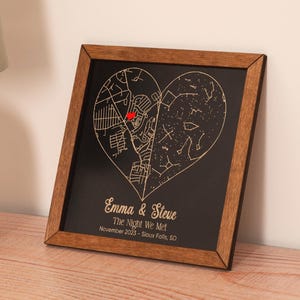 May include: A framed black and gold heart-shaped map with the text "Emma & Steve The Night We Met November 2023 - Sioux Falls, SD".