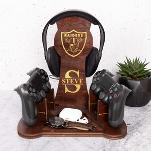 Può includere: Supporto per console da gioco in legno con logo Raiders, il nome "STEVE" inciso e spazio per due controller, un auricolare e un telefono o un orologio.