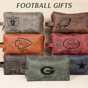 May include: A collection of leather toiletry bags in various colors, each embossed with a different football team logo and a name. The bags are in shades of gray, brown, red, and blue, with black logos and text. The text "FOOTBALL GIFTS" is at the top.