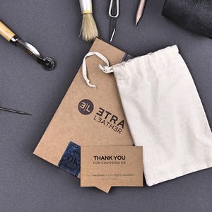 May include: A brown cardboard box with the text "Etra Leather" and a white drawstring bag. The box also has a thank you card that reads "Thank you for choosing us".