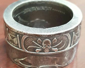 May include: A silver ring with a skull and crossbones design. The ring is engraved with a skull and crossbones, and the words "One Piece".