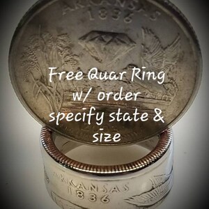 K&ouml;nnte beinhalten: Ein Silber-Viertel-Dollar-M&uuml;nzring aus einer antiken Arkansas-Viertel-Dollar-M&uuml;nze. Die M&uuml;nze zeigt einen Diamanten und die Worte "Arkansas 1836". Der Ring wird auf einer Silber-Viertel-Dollar-M&uuml;nze pr&auml;sentiert. Der Text "Free Quar Ring w/ order specify state & size" ist &uuml;ber das Bild gelegt.