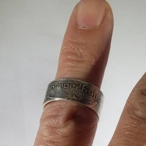K&ouml;nnte beinhalten: Ein silberner Ring aus einer M&uuml;nze mit hebr&auml;ischer Schrift. Der Ring wird an einem Finger getragen.