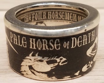May include: A silver ring with the words "PALE HORSE of DEATH" in white lettering on a black background. The ring also features a white horse graphic and the words "THE FOUR HORSEMEN OF" on the inside rim.