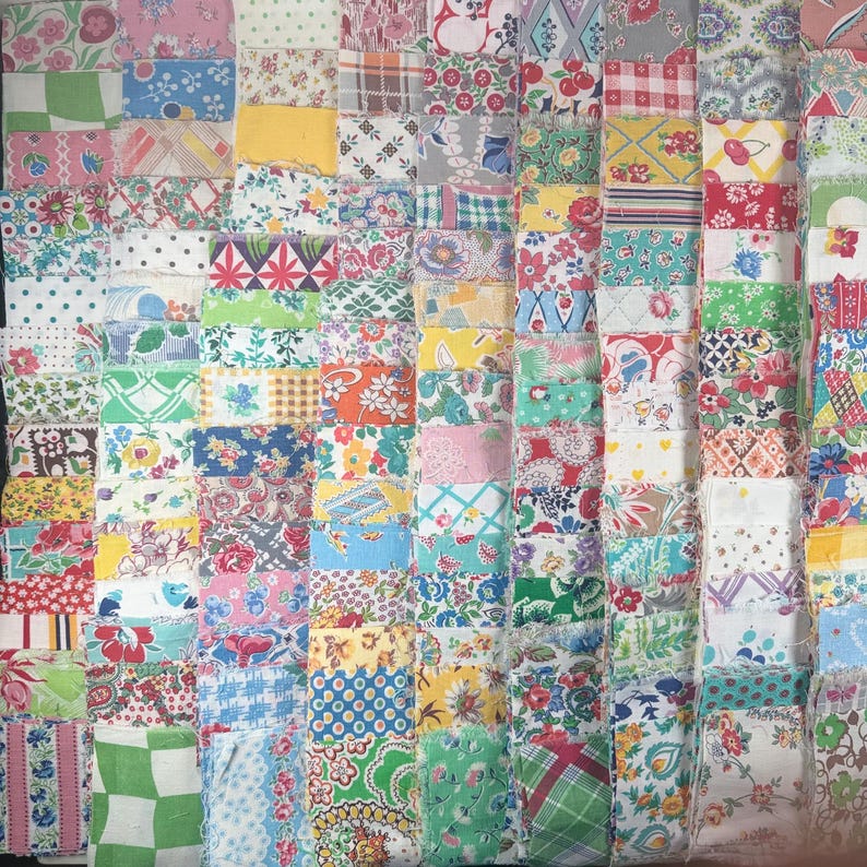 May include: A patchwork quilt composed of numerous fabric squares in various colors and patterns. The quilt features a mix of floral, geometric, and abstract designs in shades of pink, blue, green, yellow, and red. The squares are arranged in a grid-like pattern.