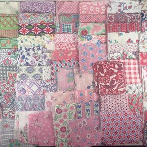 May include: A collection of folded fabric pieces in various patterns and colors. The fabrics feature floral, geometric, and abstract designs in shades of pink, red, green, purple, and white. The arrangement suggests a selection of quilting or crafting materials.