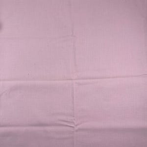 May include: A plain, pale pink fabric with a slightly textured surface. The fabric is folded, showing creases and lines. The overall look is soft and muted, suggesting a textile item.