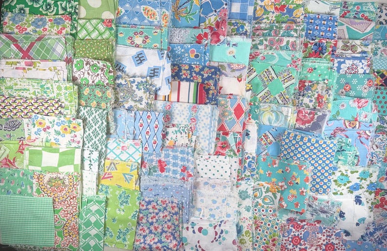 May include: A collection of vintage fabric pieces in various shades of green, blue, and white. The fabrics feature floral, geometric, and polka dot patterns. The pieces are neatly stacked, showcasing a variety of textures and designs, perfect for quilting or crafting projects.