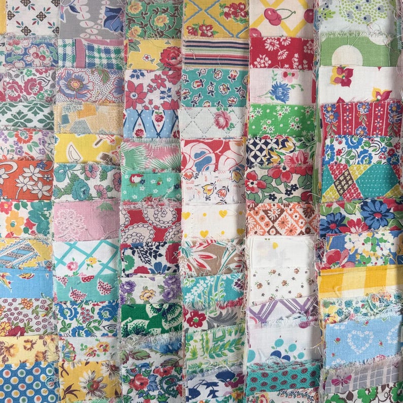 May include: A patchwork quilt composed of numerous fabric squares in various colors and patterns. The quilt features floral, geometric, and abstract designs in shades of red, blue, yellow, and green. The edges of the fabric squares are frayed.