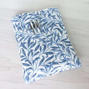 May include: A blue and white floral patterned fabric pouch with a pocket for pens or pencils.