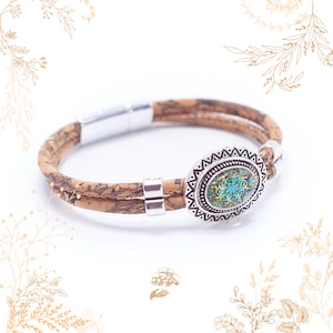 Può includere: Un braccialetto in sughero a doppio filo con un ciondolo ovale argentato con un design di mandala colorato.