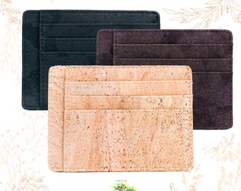 May include: Three card holders in different colors and materials. The first is black leather, the second is brown leather, and the third is cork.