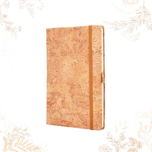 Puede incluir: Un cuaderno de corcho con cierre elástico marrón. El cuaderno tiene una cubierta de corcho natural con un sutil patrón marrón y beige.