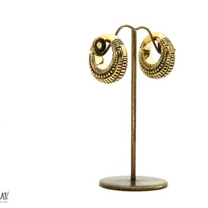 Könnte beinhalten: Ein Paar goldfarbene Creolen mit filigranen Designs. Die Ohrringe werden auf einem goldfarbenen Ständer präsentiert.