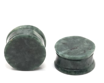 Puede incluir: Un par de dilatadores de oreja de piedra verde. Los dilatadores son redondos y tienen un acabado liso y pulido.