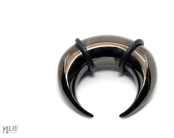 May include: A black metal ear gauge with a crescent moon shape and pointed ends. The gauge is made of surgical steel and has a black oxidized finish.