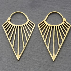 May include: A pair of gold-toned geometric hoop earrings with a triangular design. The earrings have a sunburst pattern with thin lines radiating from the centre.
