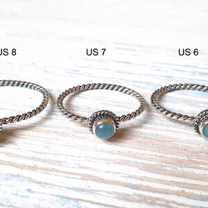 May include: Three silver rings with a light blue gemstone in the center. The rings are labeled US 8, US 7, and US 6.