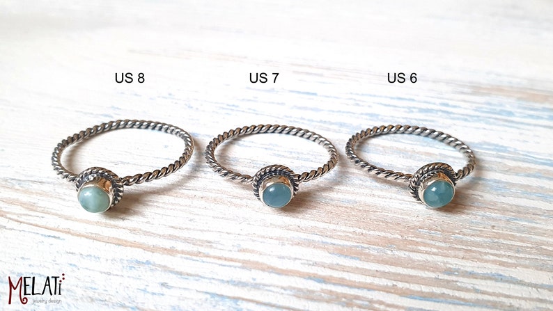 May include: Three silver rings with a light blue gemstone in the center. The rings are labeled US 8, US 7, and US 6.